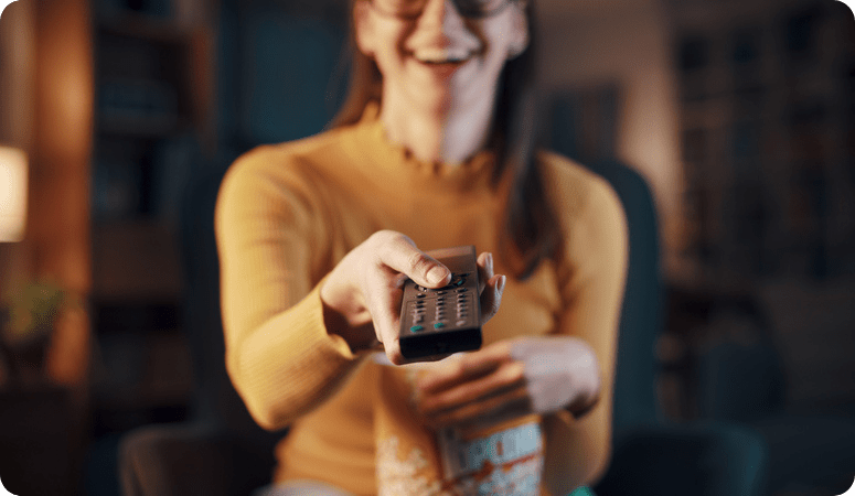 Frau zeigt mit einer Fernbedienung und lächelt