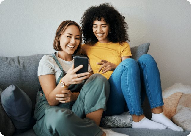 Zwei Freunde, die nebeneinander sitzen und auf ein Handy schauen